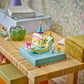 The LEGO® Creator™ 3-in-1 Unicorn Castle by Legos - Toyhouse, a vibrant castle playset, features miniature animal figures on a blue platform atop a wooden table, with boxes and decorative items in the background.