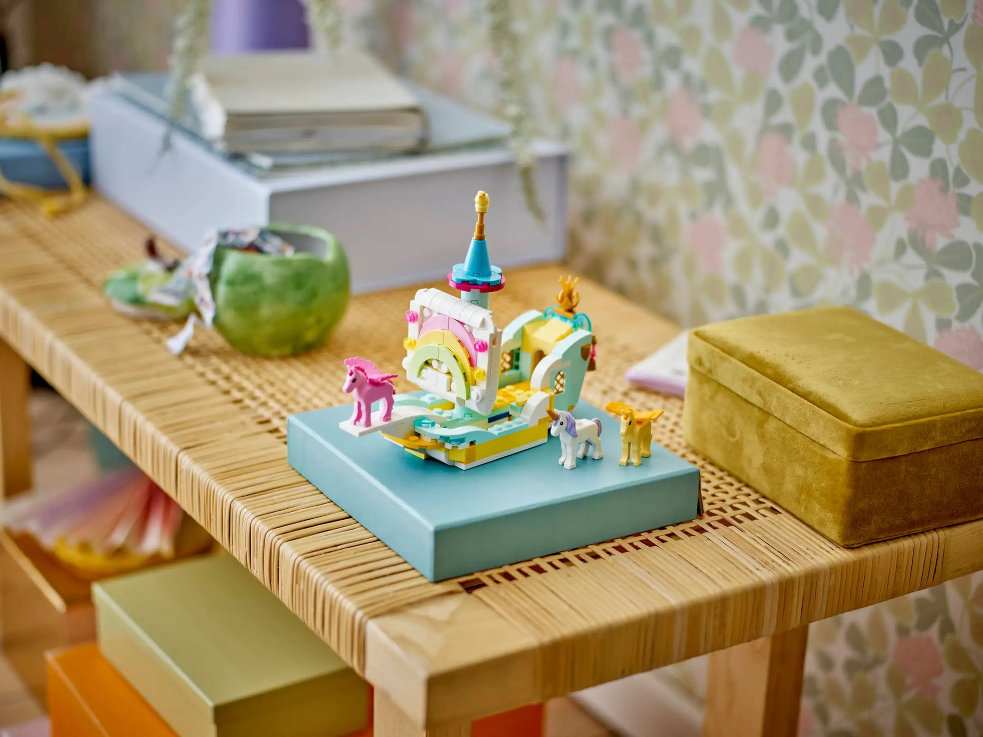 The LEGO® Creator™ 3-in-1 Unicorn Castle by Legos - Toyhouse, a vibrant castle playset, features miniature animal figures on a blue platform atop a wooden table, with boxes and decorative items in the background.