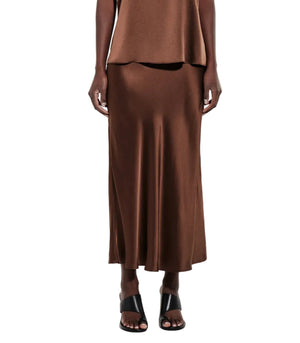 A person wearing the CO Slip Silk Skirt in brown, paired with a sleeveless top and black open-toe heeled sandals, standing against a white background.