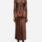 A person is shown from the back against a plain white background, wearing the CO Slip Silk Skirt in brown satin styled as a midi slip dress with thin straps and black heels, evoking the look of a classic bias-cut slip.