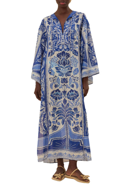 A person wearing the Farm Rio Delicate Tapestry Long Cover Up, featuring blue and white botanical patterns and wide sleeves, pairs it with brown sandals while standing against a white background.