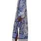 A person models the Farm Rio Delicate Tapestry Long Cover Up, a blue and white botanical-print kaftan with side slits, paired with flat sandals, standing against a white background.