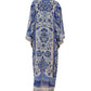 A person is shown from the back wearing the Delicate Tapestry Long Cover Up by Farm Rio, a long and loose-fitting blue-and-white garment featuring intricate botanical patterns.