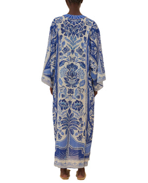 A person is shown from the back wearing the Delicate Tapestry Long Cover Up by Farm Rio, a long and loose-fitting blue-and-white garment featuring intricate botanical patterns.
