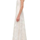 A woman stands in profile wearing the Simkhai Annabella Soutache Dress—a sleeveless white linen-blend midi with floral soutache embroidery—and strappy heeled sandals against a white background.