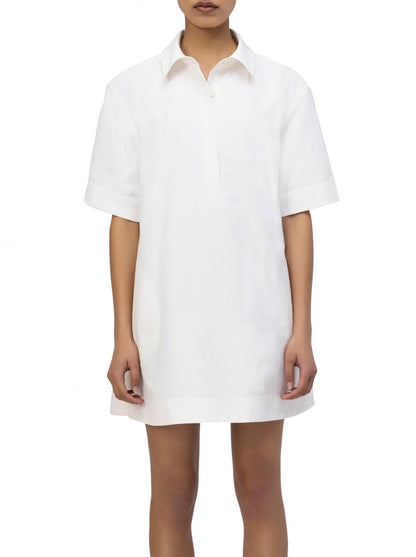 A person wearing the Simkhai Lucienne Dress, a minimalist aesthetic short sleeve mini, stands against a white background.