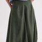 A person wears a gray long-sleeve top tucked into the TWP Full Intentions Superfine Cotton Skirt in olive green, featuring a sculpted silhouette and high waist, with hands resting casually in its pockets.