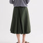 A person stands facing away, wearing a gray long-sleeve top, brown sandals, and the TWP Full Intentions Superfine Cotton Skirt—a voluminous green skirt with a flared hem—against a plain background.