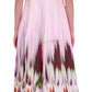 A woman is seen from the back wearing the Simkhai Magnolia Midi Dress, a sleeveless, ankle-length pink fit-and-flare style with an abstract floral print on the lower half.