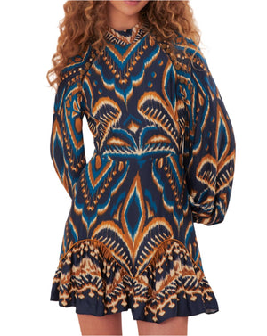 Someone wearing the Farm Rio Pineapple Ikat Blue Mini Dress, featuring a blue and orange pattern with long sleeves and a ruffled hem.