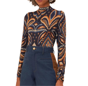 A person wearing a Farm Rio Pineapple Ikat Blue Jersey Blouse paired with high-waisted jeans featuring brown side panels.