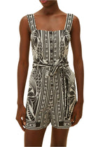 A woman showcases monochrome elegance in the Farm Rio Monochrome Elegance Scarf Off White Romper, featuring a sleeveless design, square neckline, and matching waist tie.