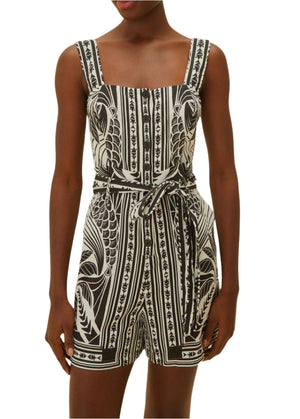 A woman showcases monochrome elegance in the Farm Rio Monochrome Elegance Scarf Off White Romper, featuring a sleeveless design, square neckline, and matching waist tie.