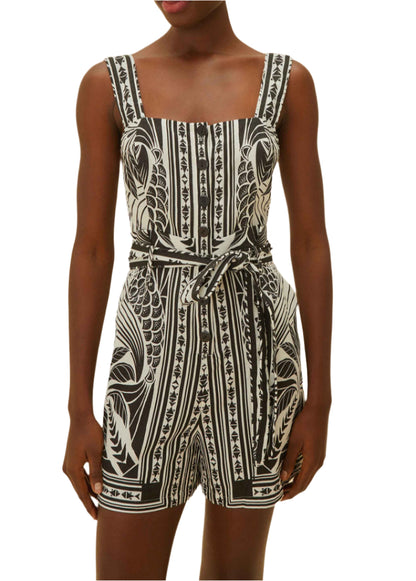 A woman showcases monochrome elegance in the Farm Rio Monochrome Elegance Scarf Off White Romper, featuring a sleeveless design, square neckline, and matching waist tie.