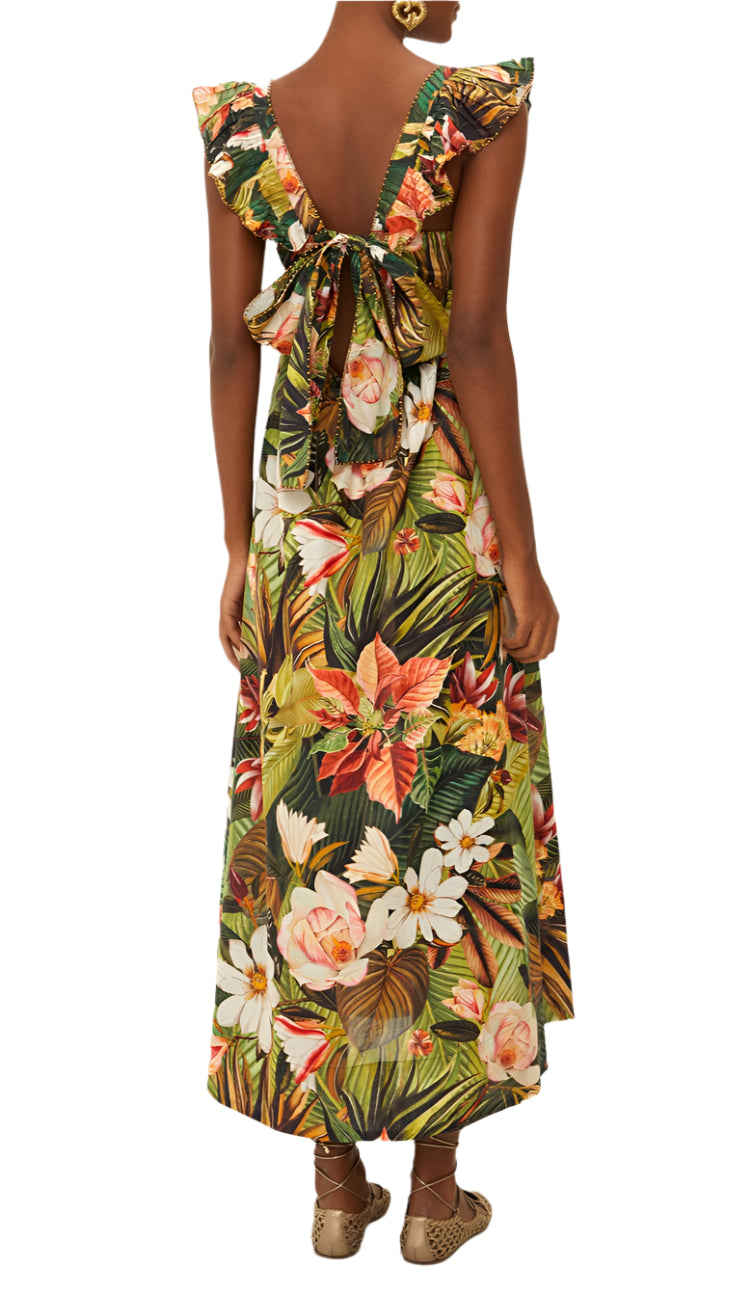 A person wears the Farm Rio Botanical Forest Multicolor Scoop Neck Ruffled Strap Dress, featuring a low back and large bow tie, paired with flat woven shoes.