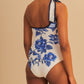 Model wears the Farm Rio Blue Floral Cascade One Piece, a chic white swimsuit with blue floral prints and a decorative shoulder bow, set against a beige background.