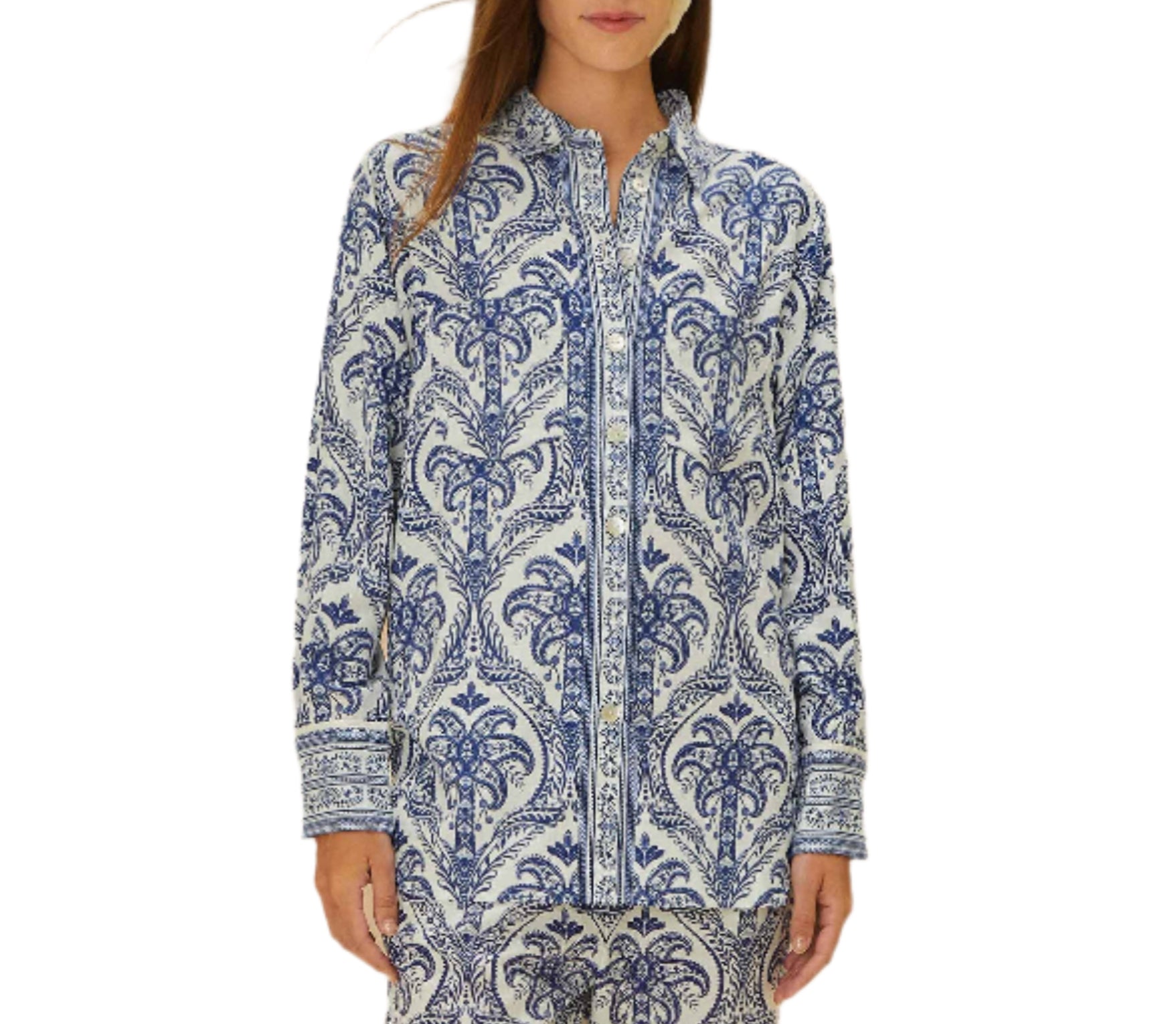 A woman wears the Farm Rio Blue Tropical Cameo Off-White Pajama Shirt, a long-sleeve, button-up top with a blue and white floral print made from LENZING™ ECOVERO™, standing against a plain white background.
