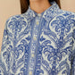 A woman wears the Farm Rio Blue Tropical Cameo Off-White Pajama Shirt, featuring an intricate floral pattern and eco-friendly LENZING™ ECOVERO™, paired with a large off-white earring.