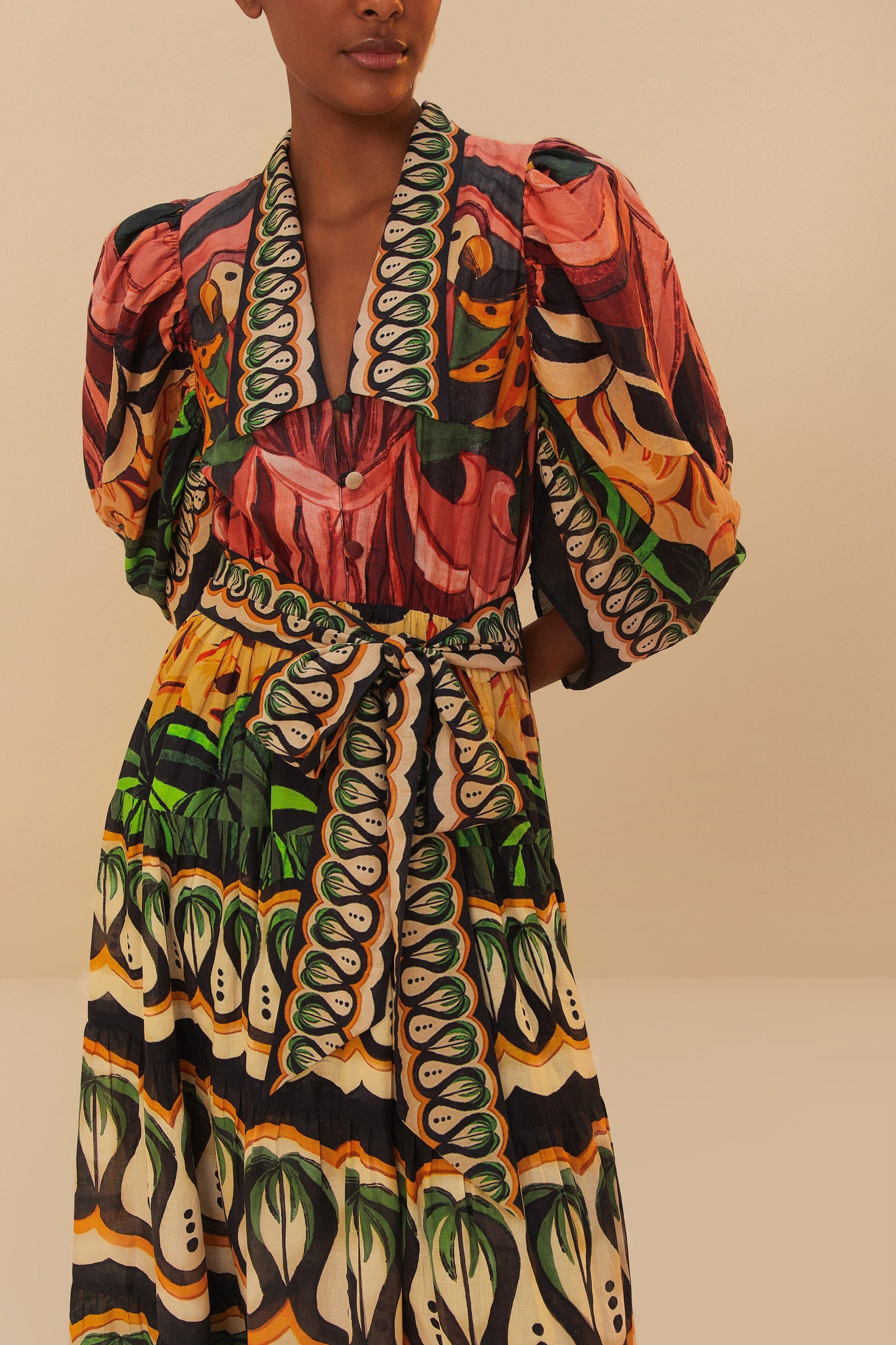 A person wearing Farm Rio's Coconut Tree Flow Dress with unique prints, puffed sleeves, and a V-neck collar stands against a neutral background.