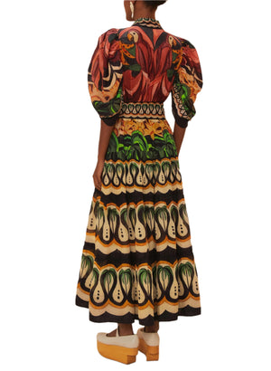 A person wearing the Farm Rio Coconut Tree Flow Dress, featuring colorful patterns, puffed sleeves, and a flared skirt, stands on wooden platform shoes facing away from the camera against a beige background.
