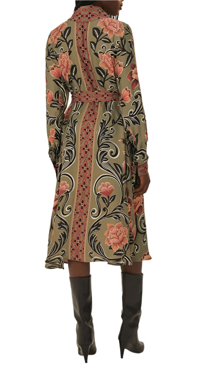 A person is wearing a Farm Rio Arabesque Floral Green Midi Dress with ruffle accents and a belted waist, featuring large pink flowers and ornate designs, paired with knee-high gray boots. The person faces away from the camera.
