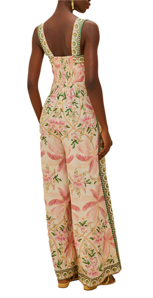 A woman wearing the Farm Rio Palm Dream Off White Jumpsuit, a sleeveless, wide-leg style with pink and green tropical patterns, photographed from the back.