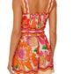 A woman is seen from the back wearing the Farm Rio Spring Affair Beige Romper, a sleeveless, belted LENZING™ ECOVERO™ piece with an orange, pink, and red floral print.
