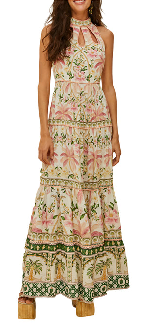 A woman wears the Farm Rio Palm Dream Off White Maxi Dress, featuring a sleeveless floral print, halter neckline, and tiered skirt, standing with her arms relaxed at her sides.