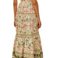 A woman wearing the Farm Rio Palm Dream Off White Maxi Dress—a long, sleeveless floral print with a tiered skirt—and platform sandals, faces away from the camera.