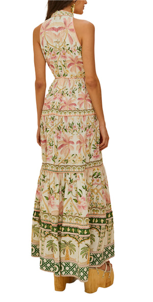 A woman wearing the Farm Rio Palm Dream Off White Maxi Dress—a long, sleeveless floral print with a tiered skirt—and platform sandals, faces away from the camera.