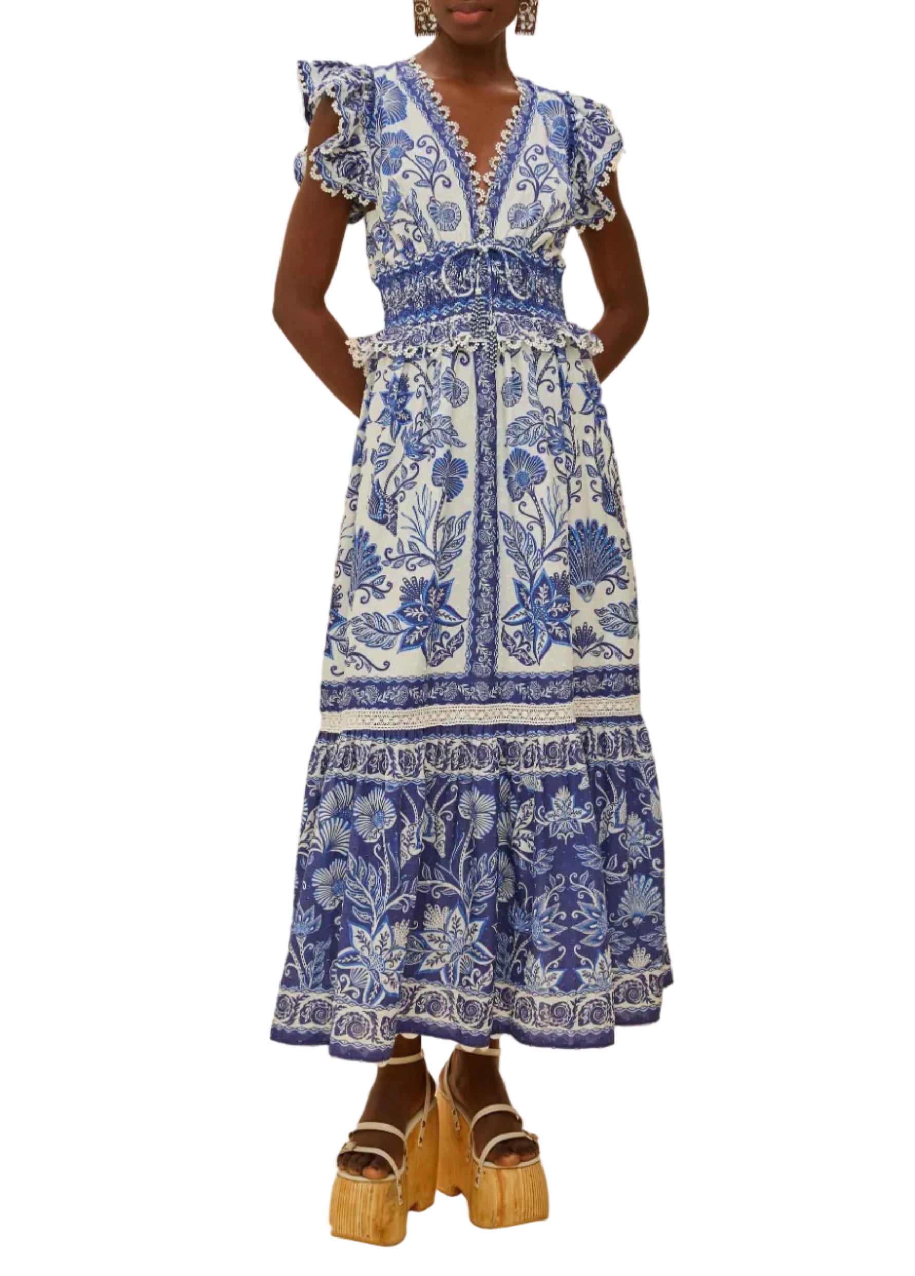 A person wearing the Farm Rio Shell Garden Off White Maxi Dress, featuring ruffled sleeves and a tiered skirt, paired with wooden platform sandals.