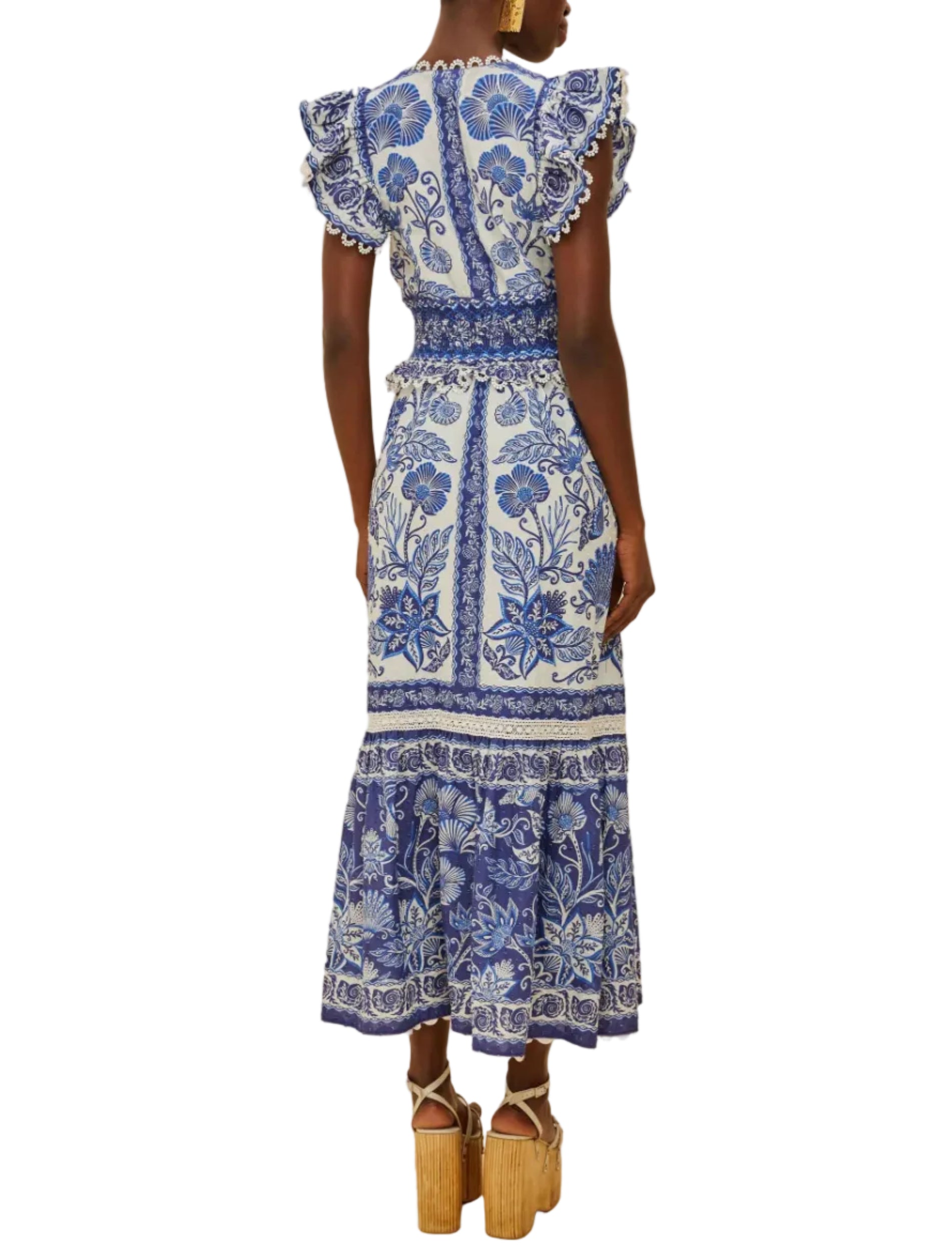 Wearing the Farm Rio Shell Garden Off White Maxi Dress—blue botanical print, ruffled sleeves, and a tiered skirt—paired stylishly with platform sandals.