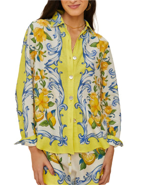Wearing the Farm Rio Sicily Scarf Off White Shirt, featuring bright yellow florals and blue-green swirls, exudes tropical elegance.
