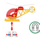 A red and yellow Brio World Firefighter Helicopter labeled "07 BRIO" hovers above two white objects with blue and red drops, indicating magnetic pickup. A magnet symbol is shown on the right, suggesting the pilot can use it to assist in water supply operations.