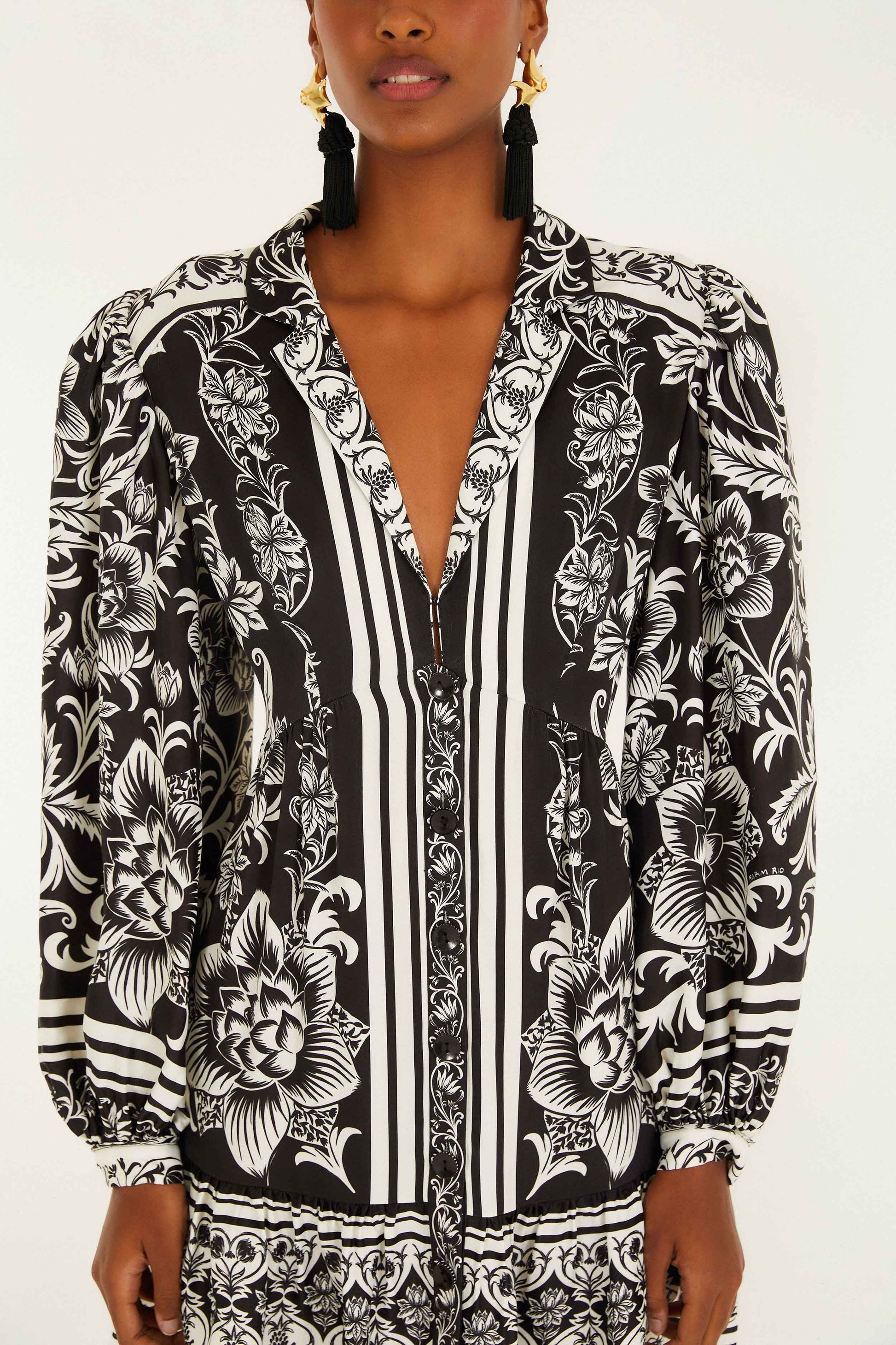 Woman wearing a Farm Rio Lisbon Black Mini Dress with black and white floral and striped patterns, featuring puffed long sleeves, crafted from lightweight fabric.