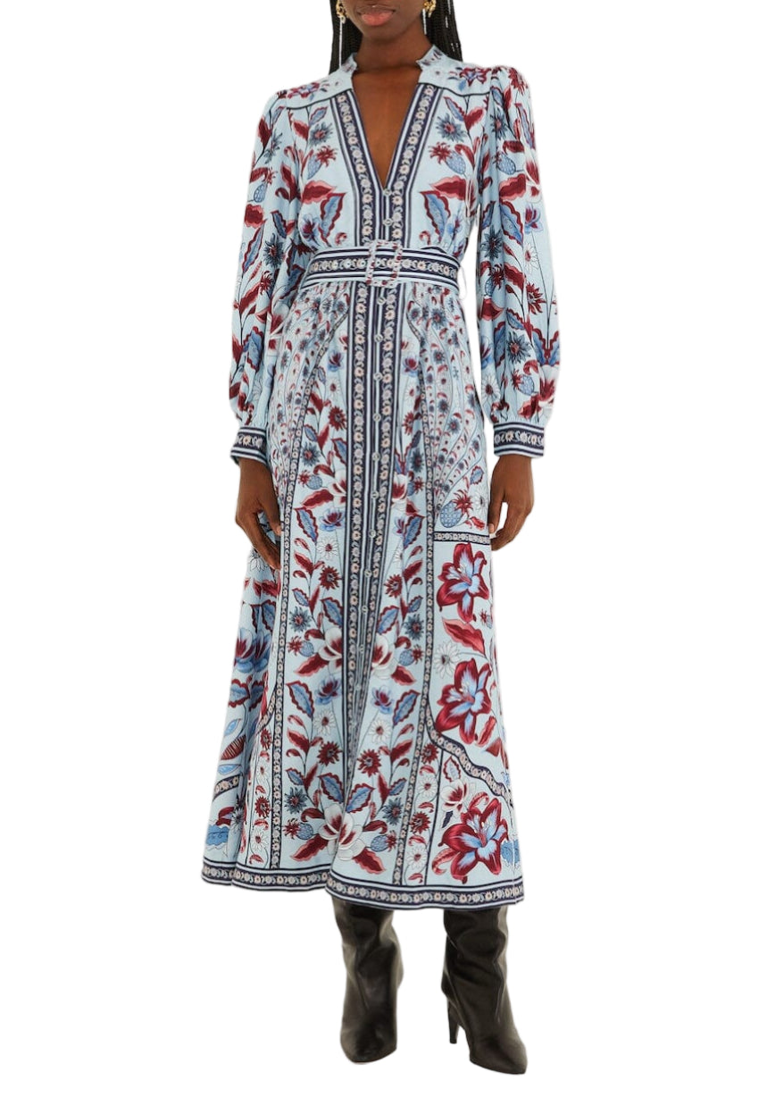 Someone wearing the Farm Rio Marcelle Maxi Dress—a long-sleeved, ankle-length dress with blue, white, and red floral and geometric patterns—paired with black boots.