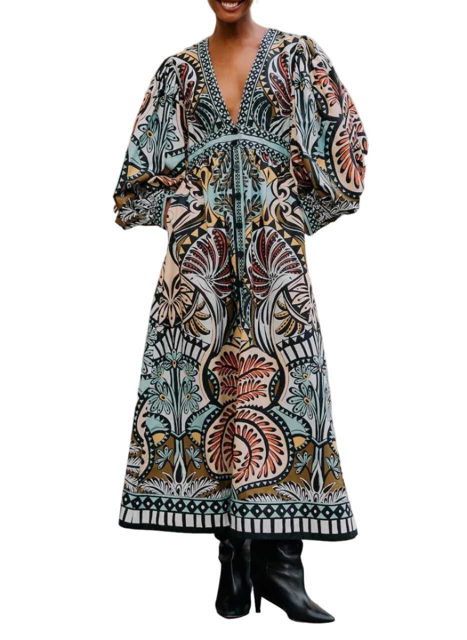 A person wears the Farm Rio Balamana Maxi Dress with voluminous sleeves, a deep V-neckline, and black heeled boots against a white background—a perfect resort-ready look.