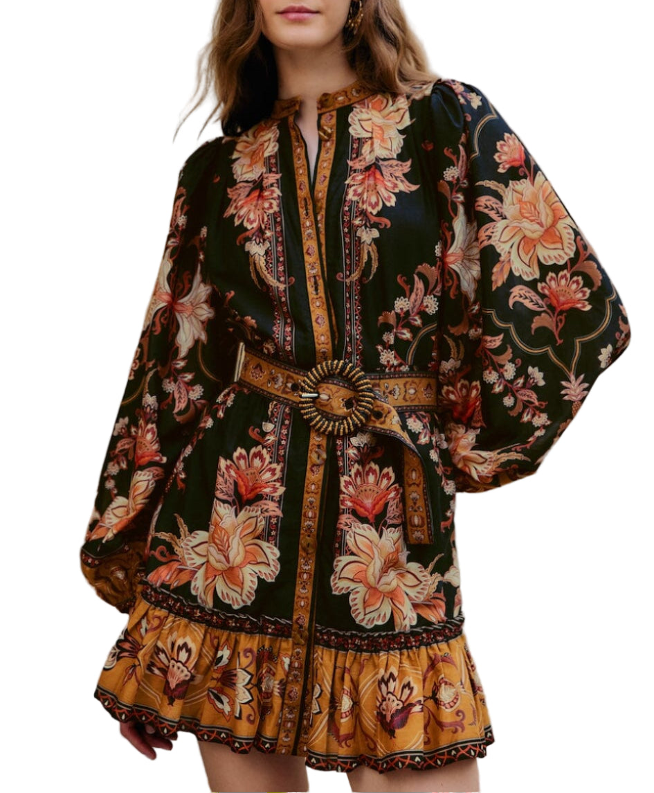 Woman wearing the Majestic Garden Black Mini Dress by Farm Rio—a floral print mini dress featuring long sleeves, a beaded buckle belt, and ruffled hem in bold black, gold, and orange.