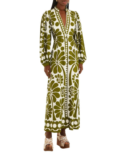 Person wearing the Palermo Green Maxi Dress by Farm Rio, featuring buttoned puff sleeves, a deep V-neck, and a green and white floral pattern, paired with brown platform sandals.