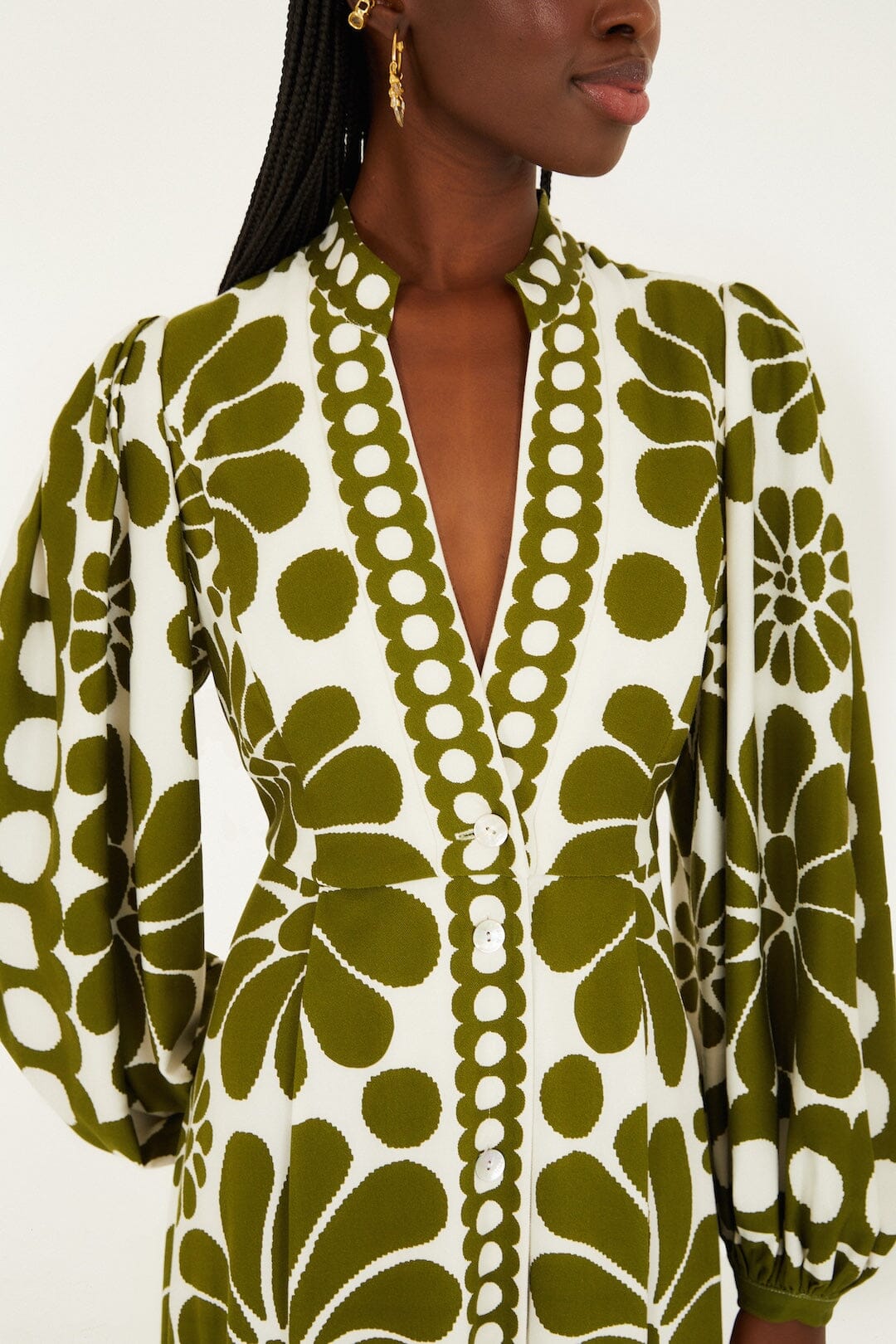 A woman wears the Farm Rio Palermo Green Maxi Dress, featuring a buttoned puff sleeve design, olive floral patterns, and a deep V-neckline with white front buttons.