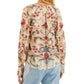A person is shown from the back wearing a long-sleeved Farm Rio Royal Garden Sand Blouse with pastel and red floral patterns, paired with light blue jeans.