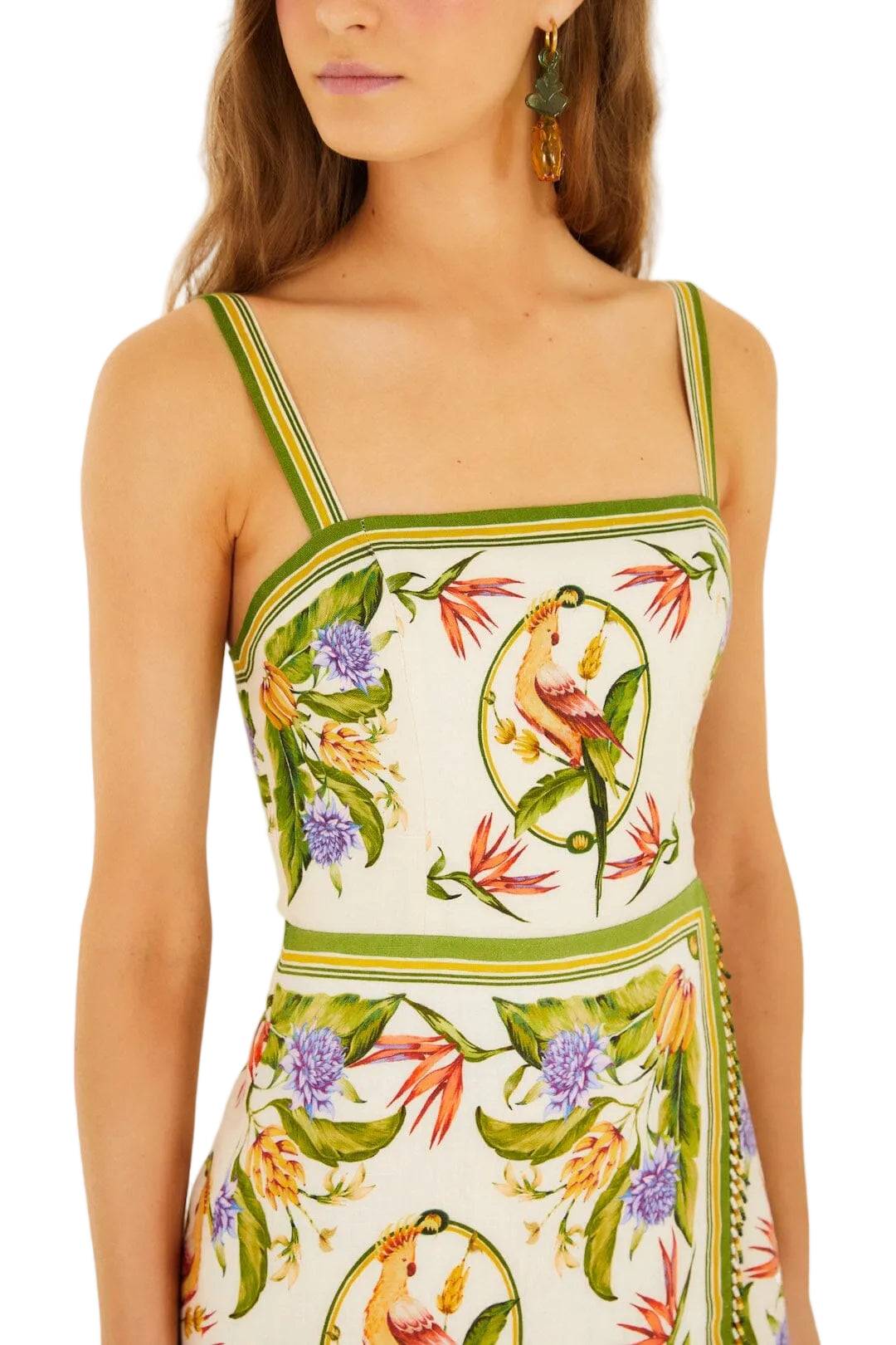 A woman wears the Farm Rio Sand Tropical Scarf Sleeveless Mini Dress, a premium linen mini with green trim and a vibrant botanical and parrot print.