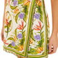 A close-up of the Farm Rio Sand Tropical Scarf Sleeveless Mini Dress, showcasing its vibrant floral print, green borders, and bead fringe detailing along the hem.