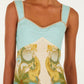 A woman wears the Farm Rio Royal Sea Multicolor Maxi Dress, featuring aqua blue straps, a sweetheart neckline, and a tropical palm tree and seashell print.