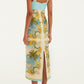 A woman stands facing away in the Farm Rio Royal Sea Multicolor Maxi Dress—a sleeveless, fitted linen dress with a blue bodice, ornate multicolored skirt, and sweetheart neckline—paired with heeled sandals.