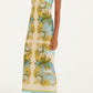 A woman wears the Farm Rio Royal Sea Multicolor Maxi Dress, featuring a sleeveless design with a blue and yellow baroque and palm leaf pattern, sweetheart neckline, paired with beige sandals.