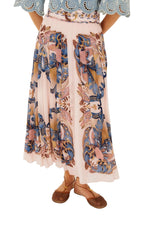 A person wears the Farm Rio Sea Garden Scarf Soft Pink Maxi Skirt with blue and brown designs, a blue scalloped top, and brown flat sandals, standing against a white background.