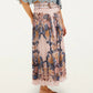 A person in a blue lace top, Sea Garden Scarf Soft Pink Maxi Skirt by Farm Rio, and brown woven flats stands against a plain background.