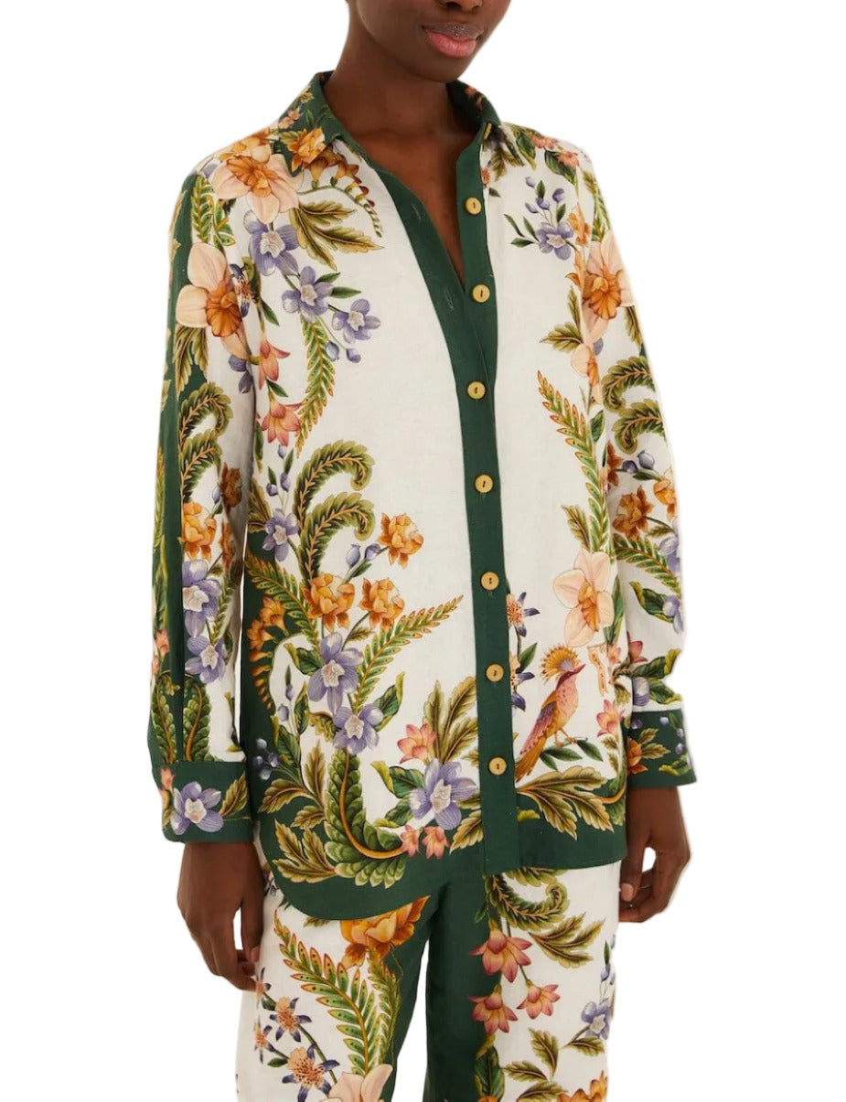 A person wearing the Farm Rio Nature Sand Shirt with matching pants, featuring a colorful floral and bird print on a white and green background.