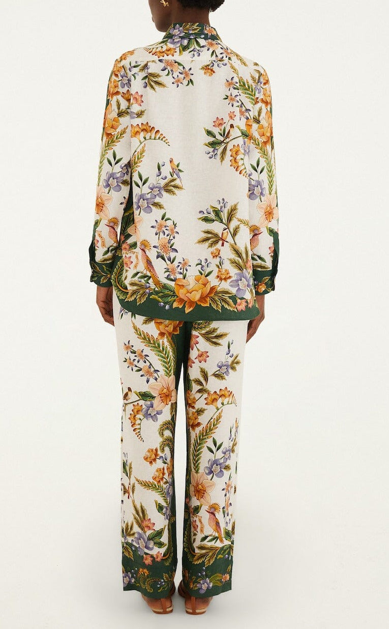 A person stands facing away, wearing a matching long-sleeve top and Farm Rio Nature Sand Pants, which feature a colorful floral pattern on a white background.